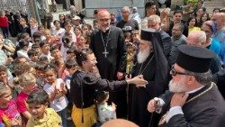 El Patriarca Latino de Jerusalén Pizzaballa y el Patriarca Griego Ortodoxo Teofio III recibidos por los niños de Gaza.