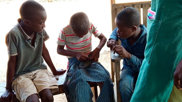Ni&ntilde;os en el centro aprenden el arte del zapatero bajo la supervisi&oacute;n del maestro, por Francisca S&aacute;nchez
